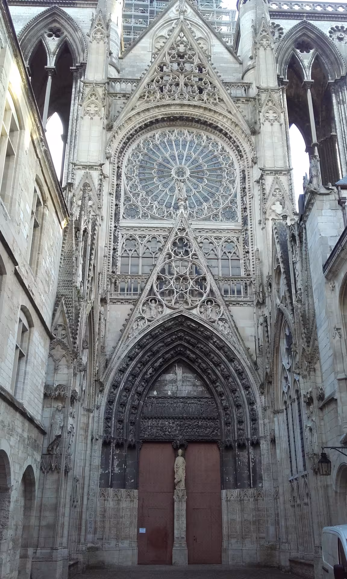 Gothic portal and rose window of Rouen Cathedral with ornate stone carvings and red wooden doors