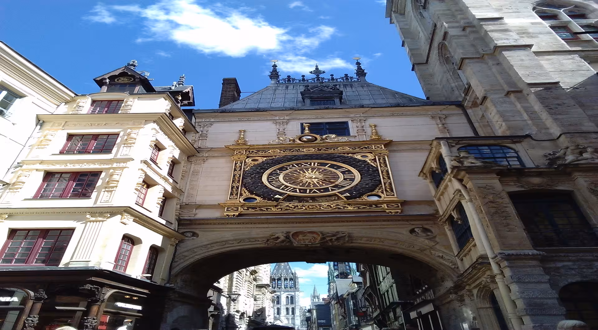 Gros Horloge astronomical clock on Renaissance arch spanning Rouen street with cathedral spires beyond