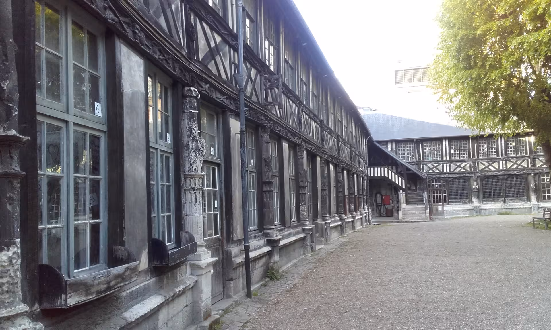 Historic half-timbered medieval building courtyard in Rouen, France, with dark wooden beams and stone facade