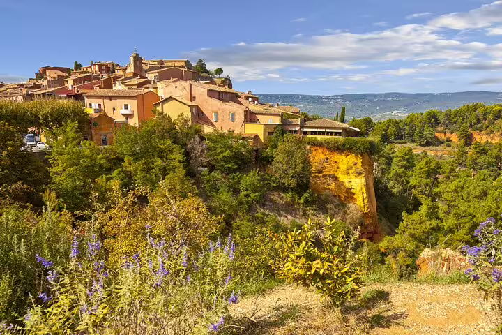Hilltop village of Roussillon with ochre cliffs and purple wildflowers in the Luberon, Provence