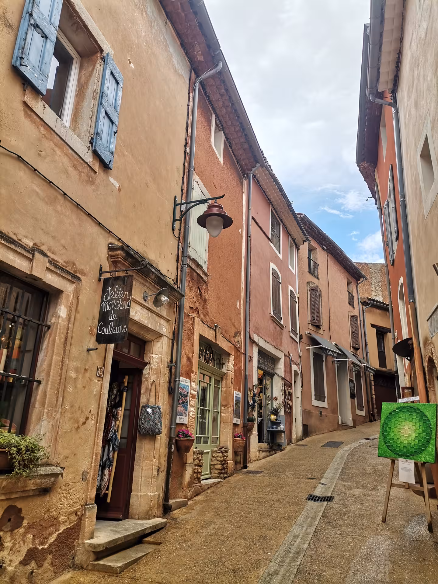 Charming Roussillon street with pastel façades and artisan shops, perfect stroll on a Provençal Picnic Tour