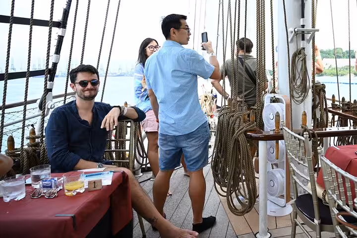Passengers capturing moments on the Royal Albatross breakfast cruise, surrounded by nautical ropes and ocean views.