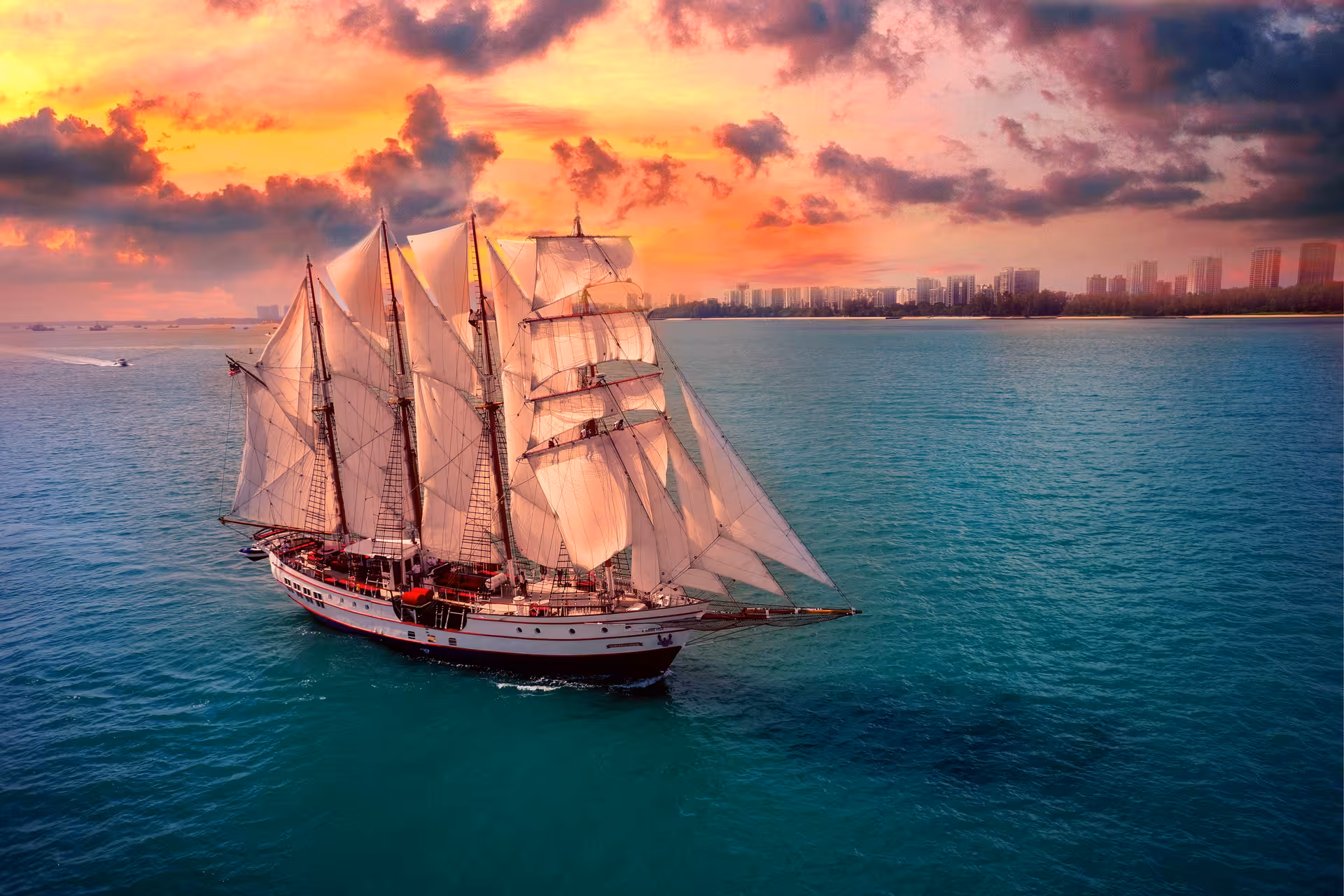 Majestic tall ship sails through turquoise waters against a vibrant sunset on the Royal Albatross Dinner Cruise.