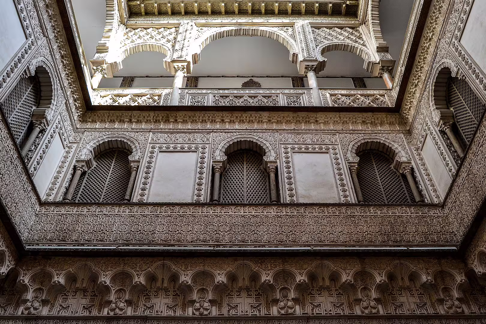 Intricate Moorish arches and detailed carvings in the Royal Alcazar of Seville courtyard, ideal for private guided tours.