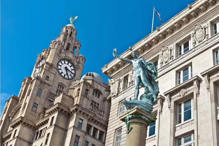 Royal Liver Building clock tower and bronze statue on Liverpool waterfront under blue sky