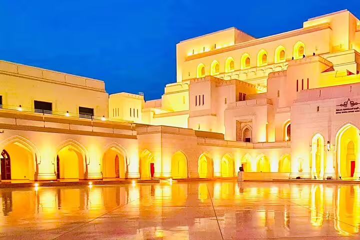 Illuminated Royal Opera House Muscat at night, highlighting its stunning architecture and elegant arches.