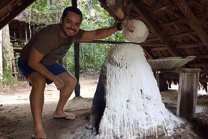 Visitor at Rubber Museum from Manaus viewing traditional latex smoking dome in an Amazon rainforest hut