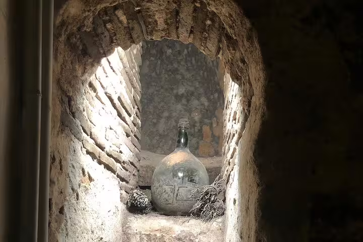 An old glass wine jug stored in a rustic brick alcove at a Rueda vineyard showcasing historical wine aging techniques.