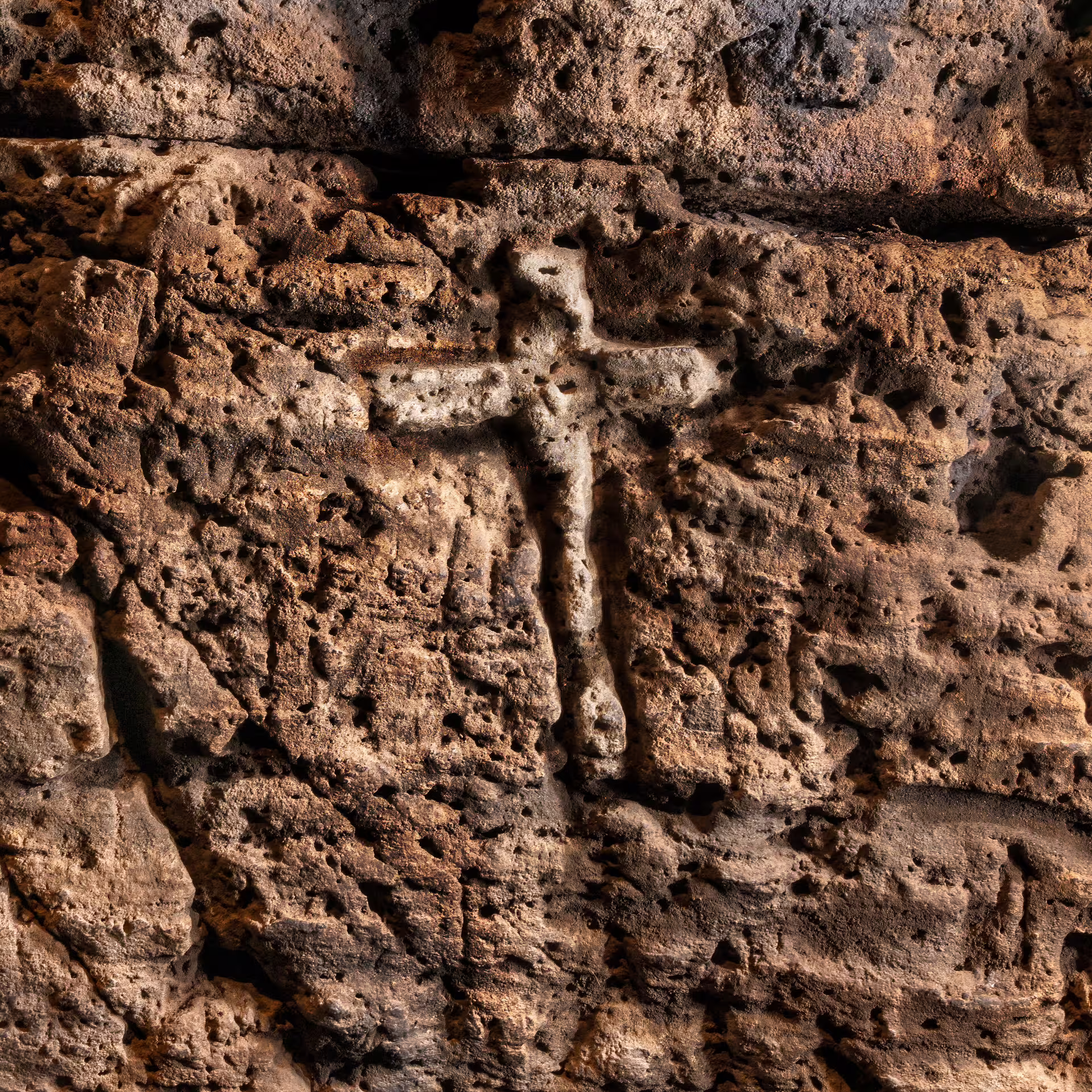 Ancient runic cross carved into weathered volcanic stone wall revealing Iceland witchcraft and Norse magic symbols