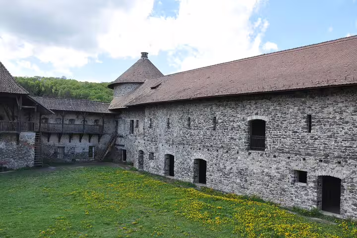 Stone courtyard and tower of Rupea Fortress with green grass and wildflowers, Transylvania