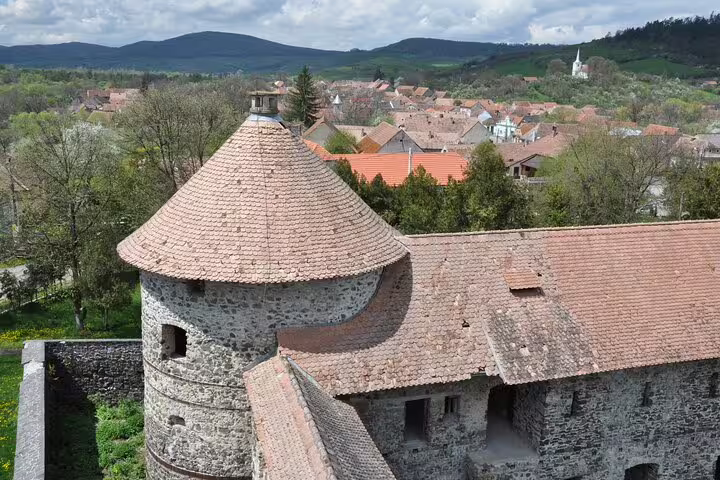 Stone tower with conical terracotta roof at Rupea Fortress overlooking a small Transylvanian village