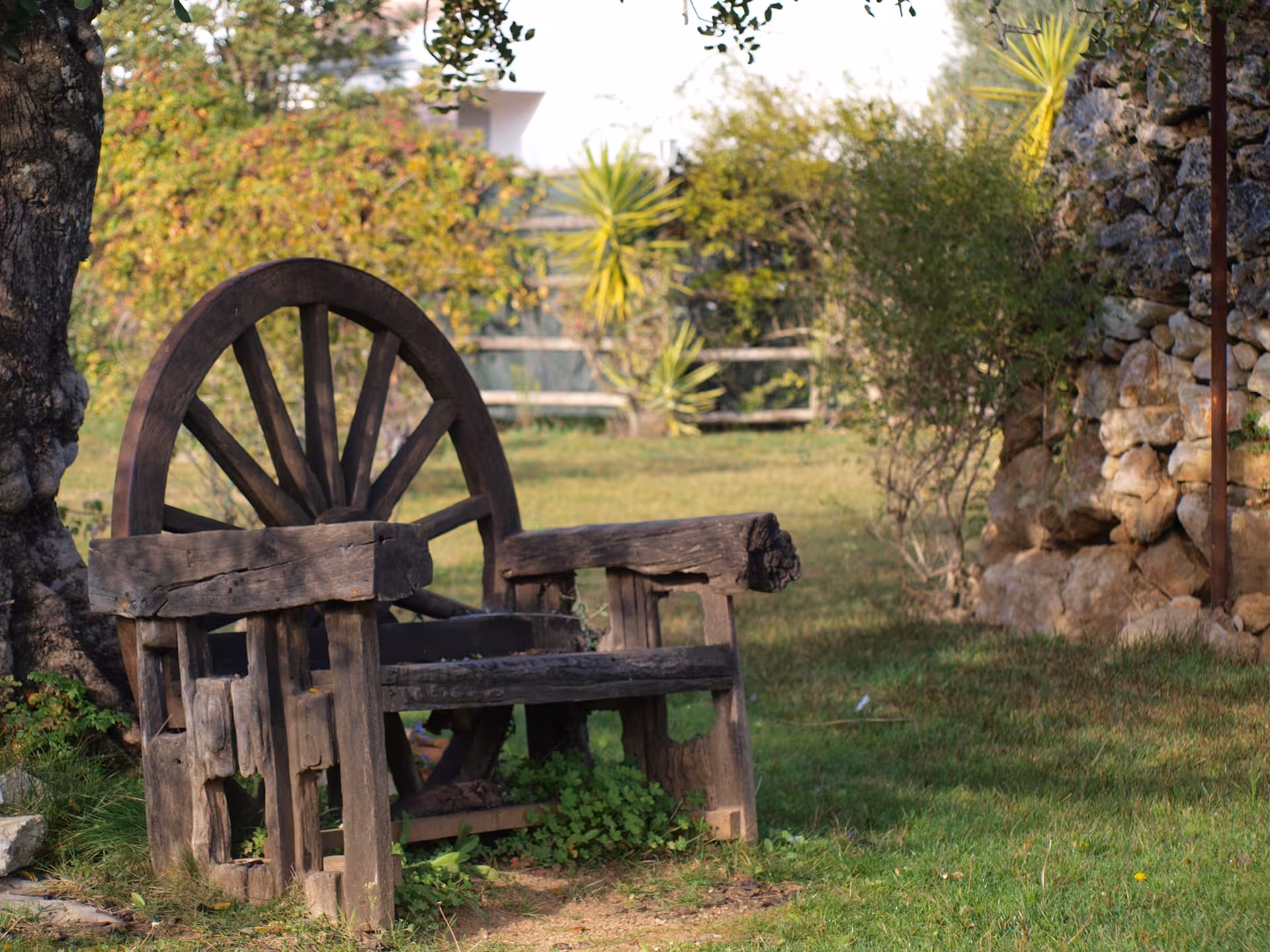 Rustic wooden bench made from an old cartwheel in a sunlit Algarve farmhouse garden, evoking traditional rural charm