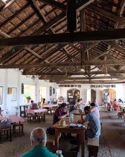 Rustic dining experience in Herdade Alentejana with guests enjoying traditional Portuguese cuisine under wooden beams.