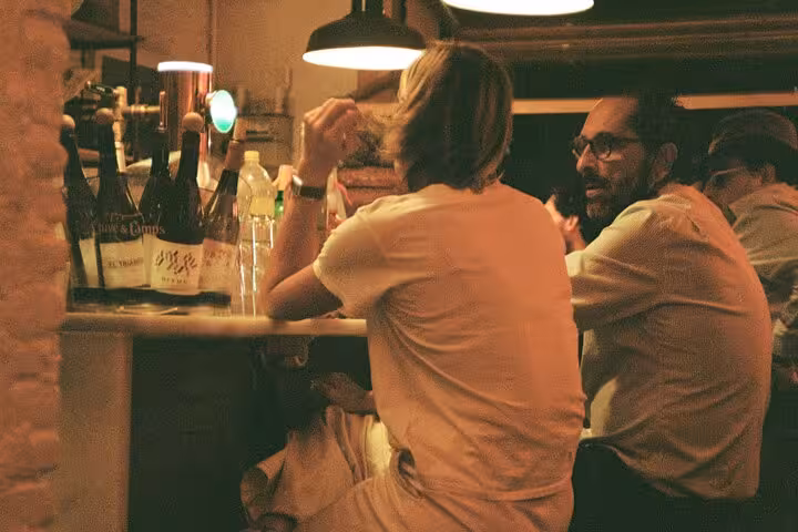 Guests chatting at a cozy Valencia wine bar during Ruzafa evening tapas tour with local wines and drinks