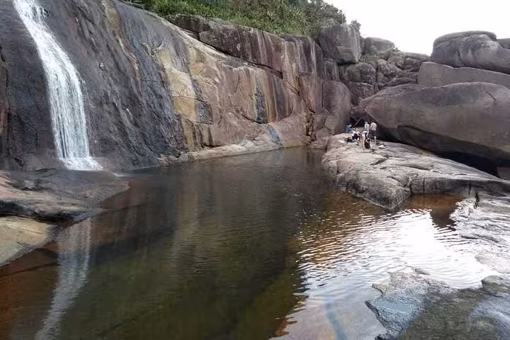 Picturesque scene of Saco Bravo Waterfall flowing into a calm pool amidst rocky terrain, a highlight of Paraty adventure tours.