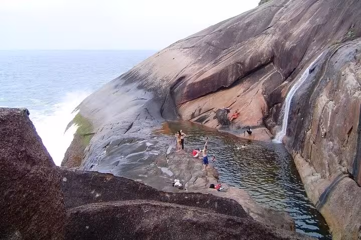 Visitors enjoying the natural pool and waterfall at Saco Bravo, a highlight of the Paraty Tours adventure experience.
