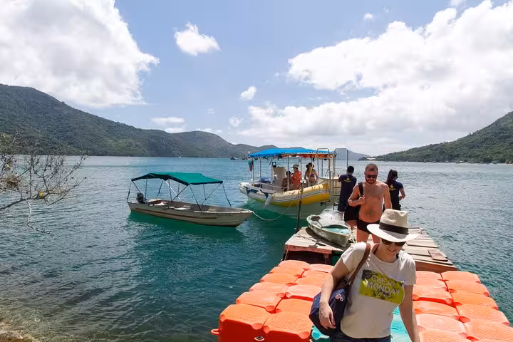 Tourists disembark from colorful boats at Saco Mamanguá Fjord, ready to explore the scenic beauty of Brazil's beaches.