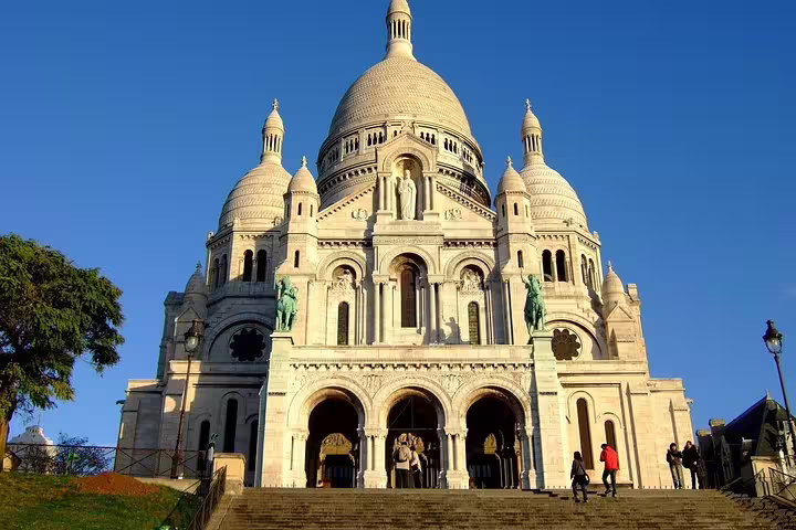 Sacré-Cœur Basilica facade with white domes and steps in Montmartre, Paris on a clear day