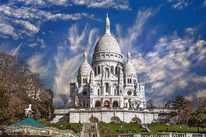 Sacré-Cœur Basilica white domes under dramatic blue sky on Montmartre hill, Paris