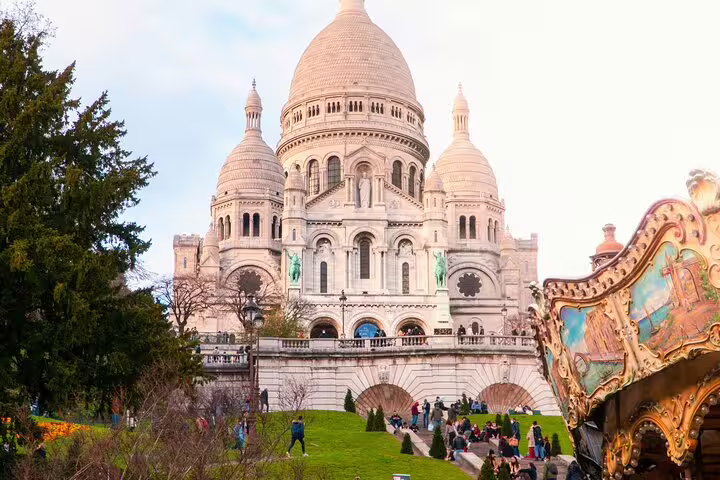 Sacré-Cœur Basilica in Montmartre Paris with a vintage carousel and green lawns