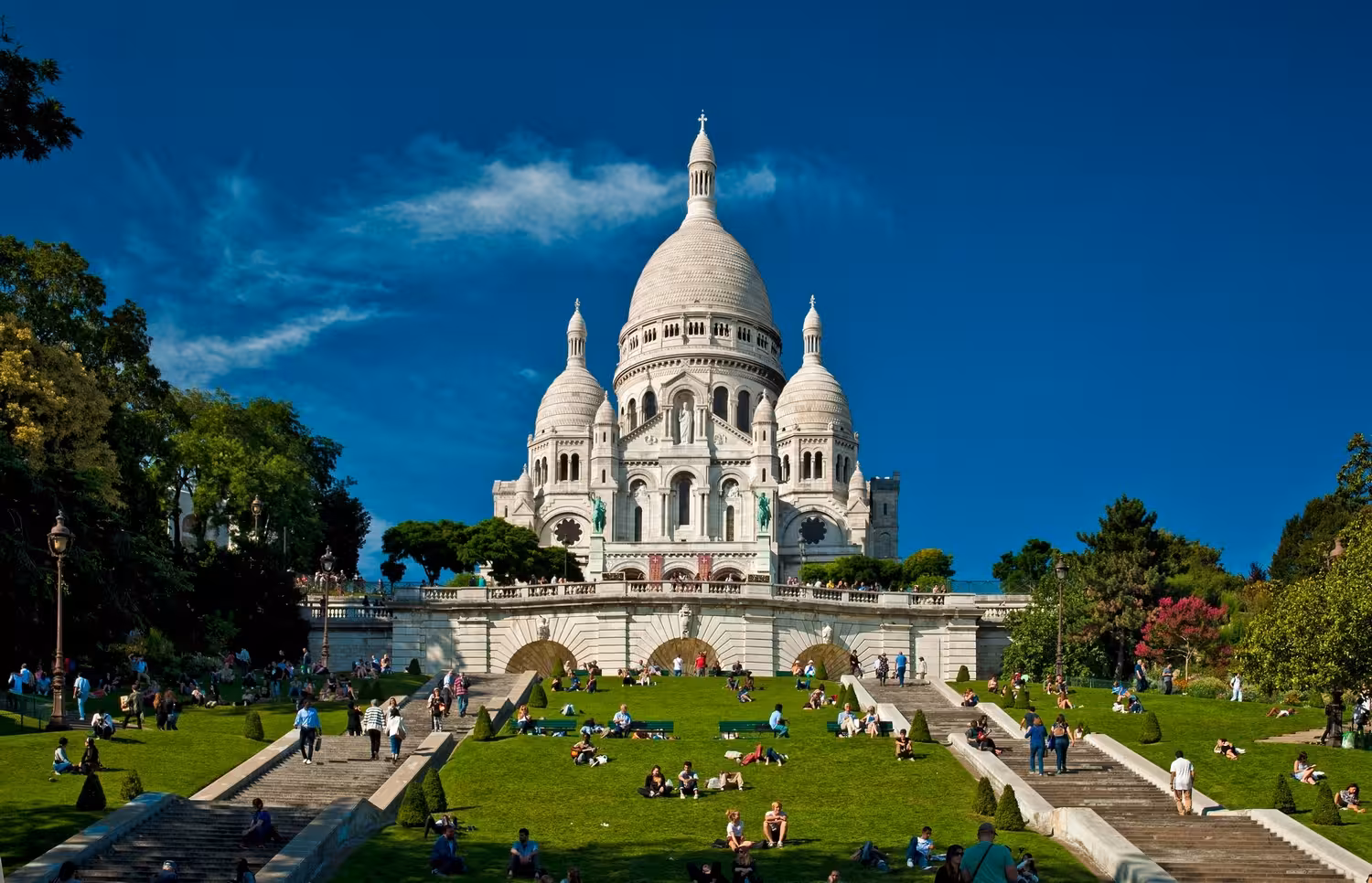 Sacre-Coeur Basilica surrounded by green lawns and visitors, a highlight of the Montmartre Food and Wine Tour.