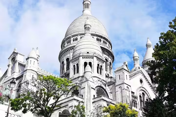 Sacré-Cœur Basilica white domed architecture surrounded by green trees in Montmartre Paris