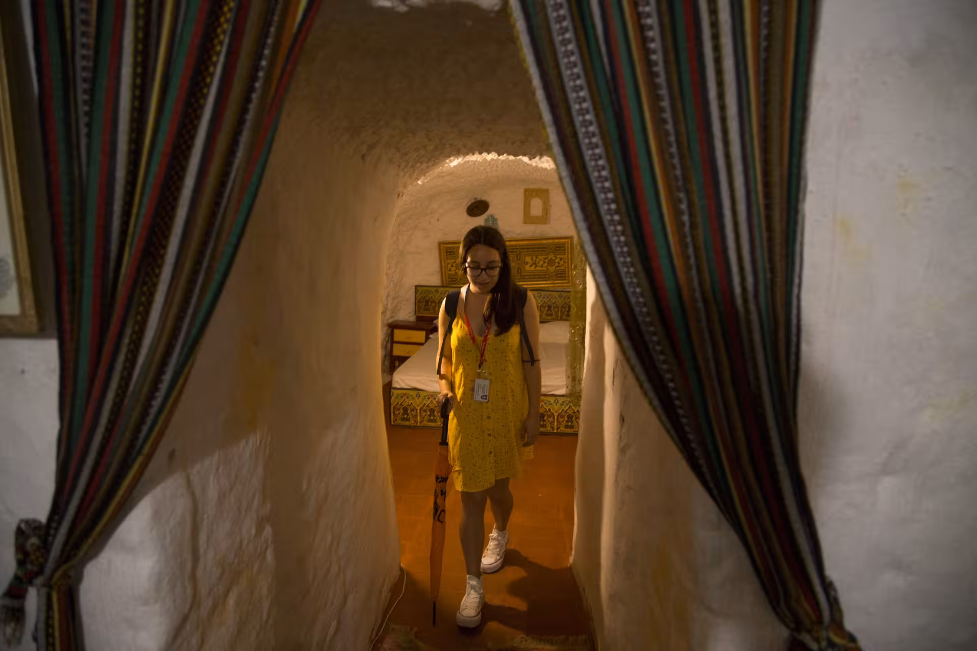 Visitor exploring a traditional cave house interior in Sacromonte, featuring rustic decor and a cozy atmosphere.