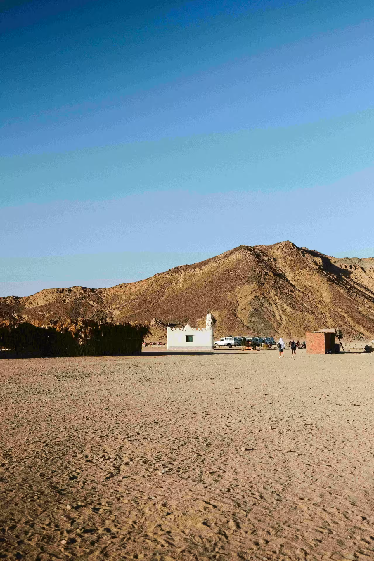 Desert landscape with white Bedouin village mosque and rocky mountain backdrop near Safaga, Egypt