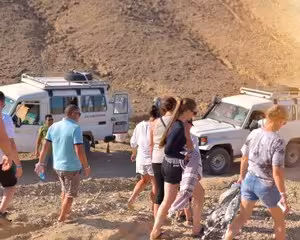 Tourists walking near white jeeps in desert landscape during Safaga jeep safari excursion