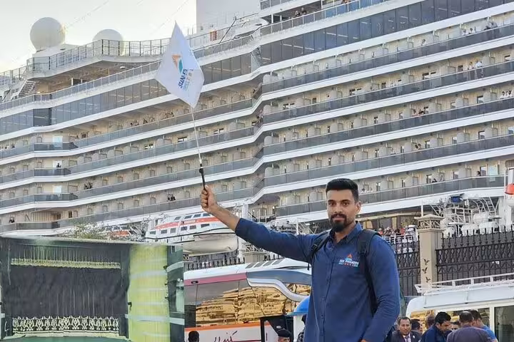 Safaga Port tour guide with flag beside cruise ship, private transfer for Luxor temples and royal tombs day trip
