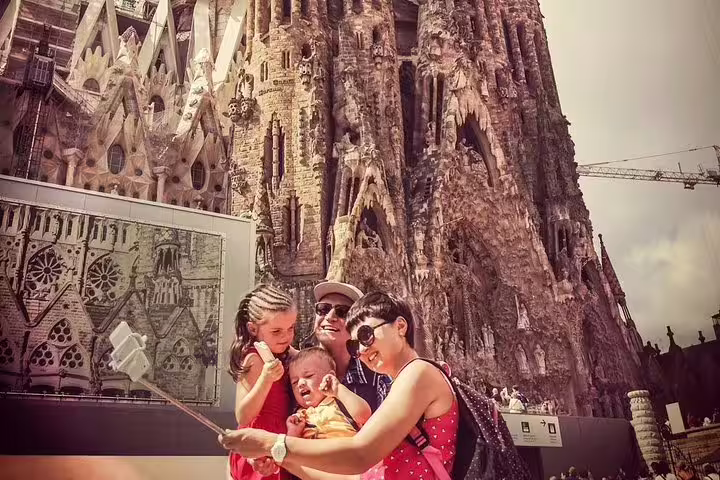 Family taking a selfie in front of the iconic Sagrada Familia during a private Gaudi tour with skip-the-line tickets in Barcelona.