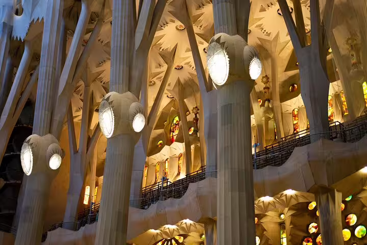 Illuminated interior pillars and stained glass of Sagrada Familia, showcasing architectural marvels on the guided tour.