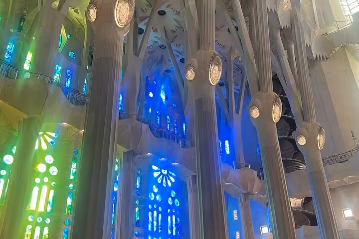 Interior of Sagrada Familia in Barcelona, showcasing vibrant blue and green stained glass windows and intricate columns.