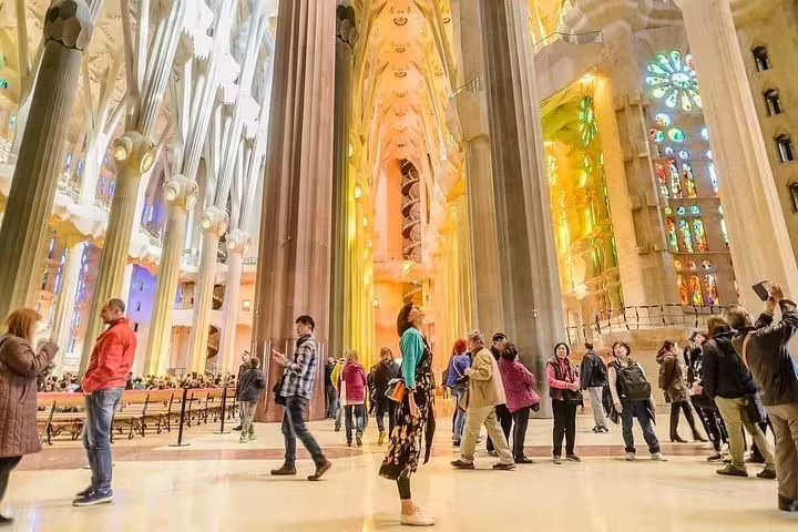 Tourists admire the breathtaking interior of Sagrada Familia with its colorful stained glass windows.