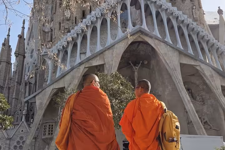 Two Buddhist monks in orange robes admiring Gaudi's Sagrada Familia facade during a Barcelona architecture walking tour