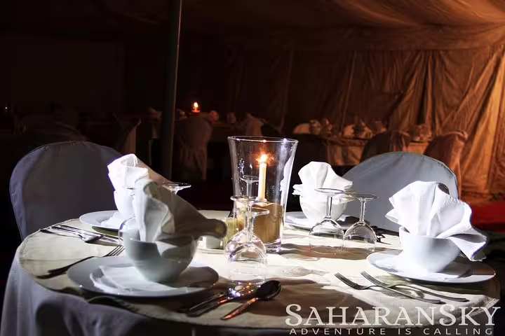 Elegant candlelit dinner setup in a desert tent, offering a unique dining experience under the Saharan sky.