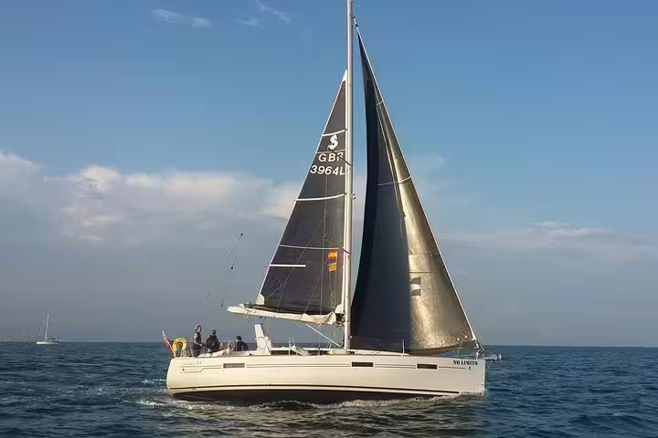Sailboat gliding on open sea under clear skies, perfect for a 2-hour sailing trip with drinks, snacks, and swimming.