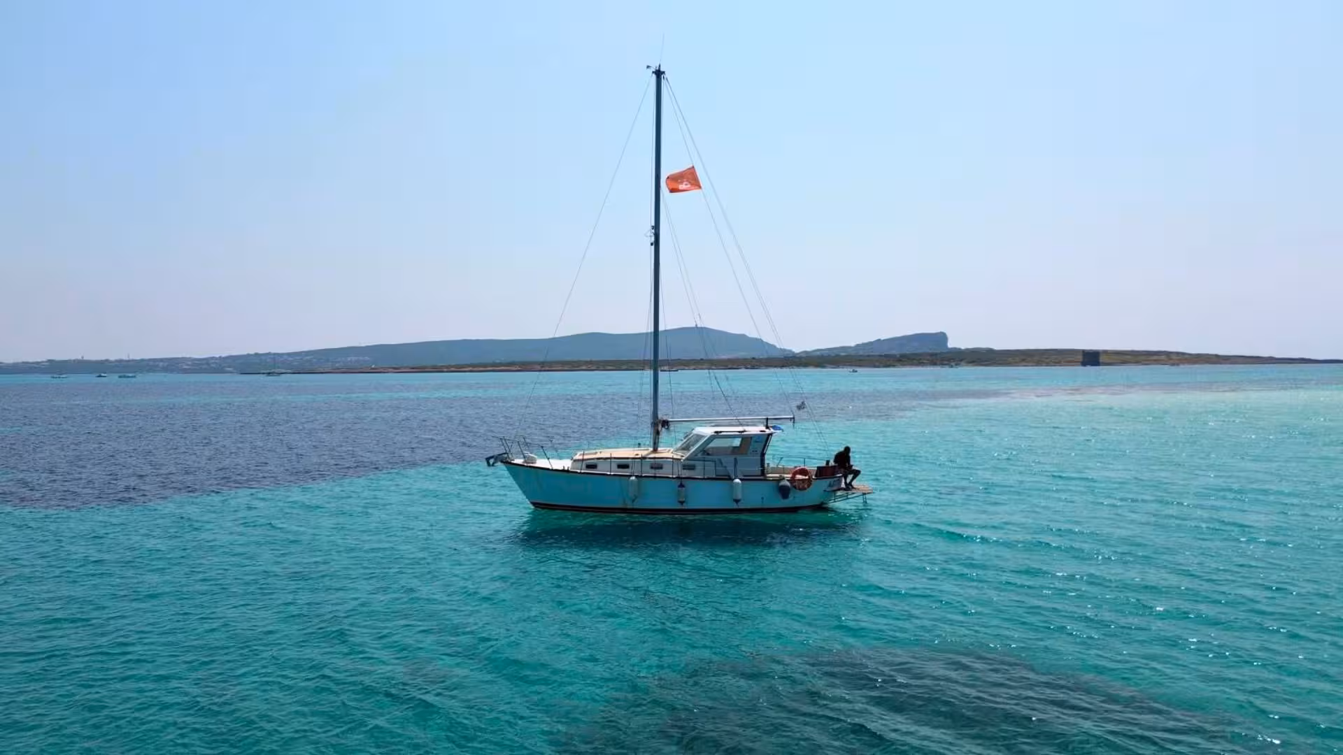 Sailboat gliding on turquoise waters in Asinara National Park, showcasing serene views and a perfect sailing adventure.