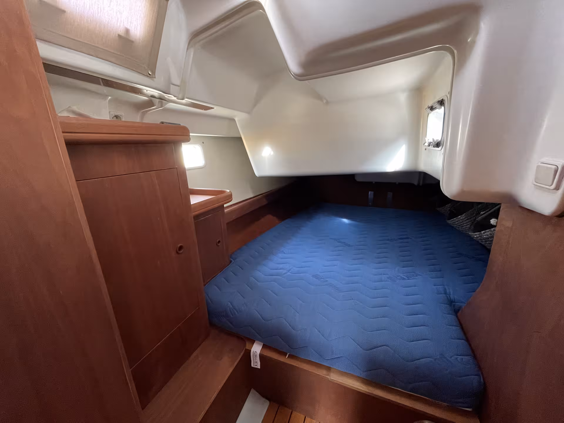 Cozy double berth cabin with blue mattress and wooden interior on a French Riviera sailboat