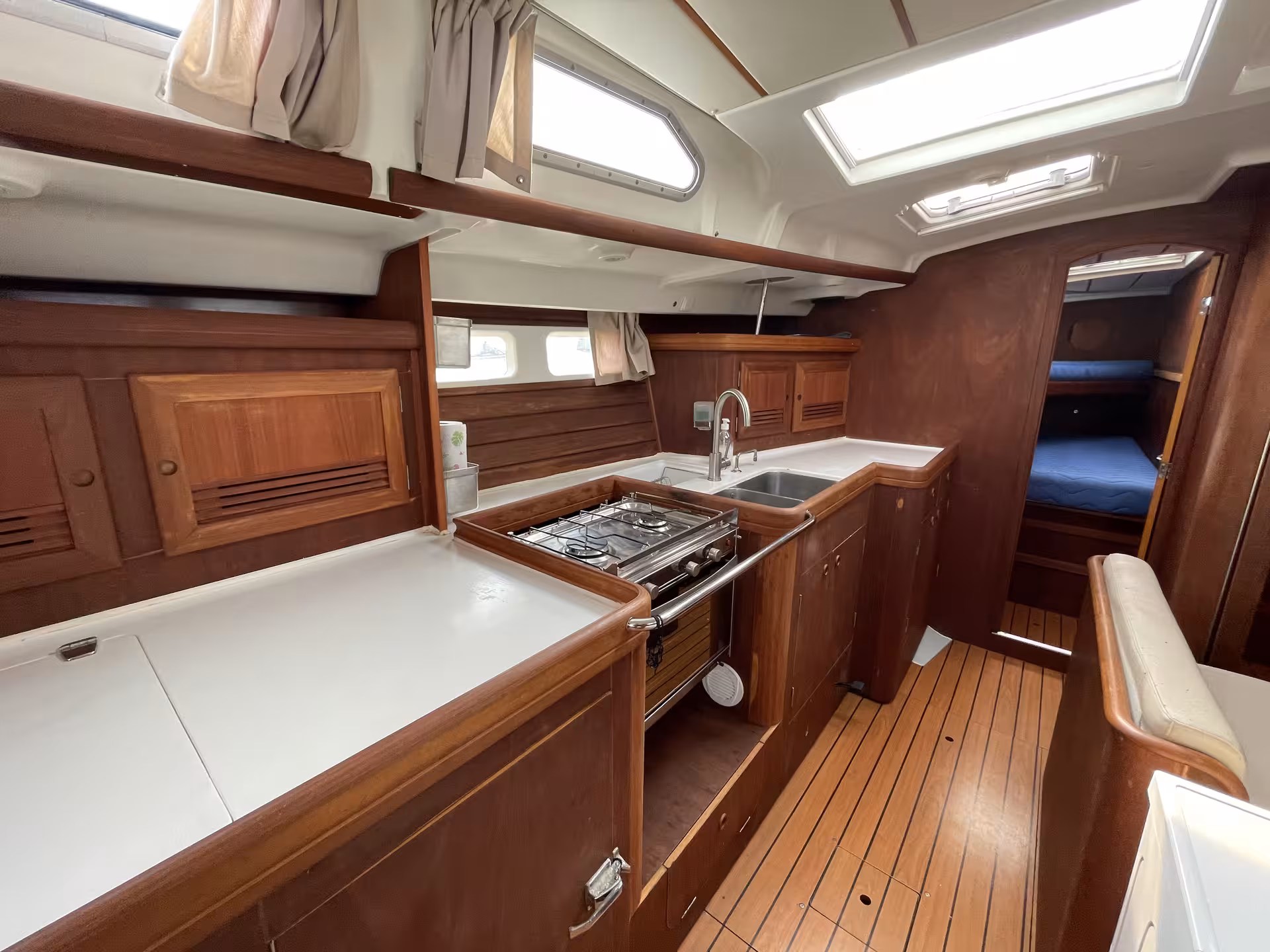 Elegant teak wood galley kitchen with stove, sink, and sleeping cabin aboard a French Riviera sailboat