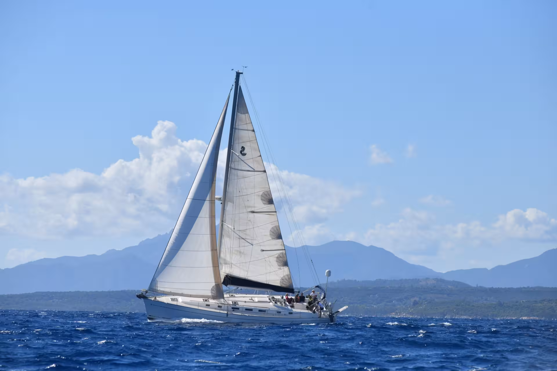 Elegant sailboat cruising in the Gulf of Orosei with mountainous backdrop.