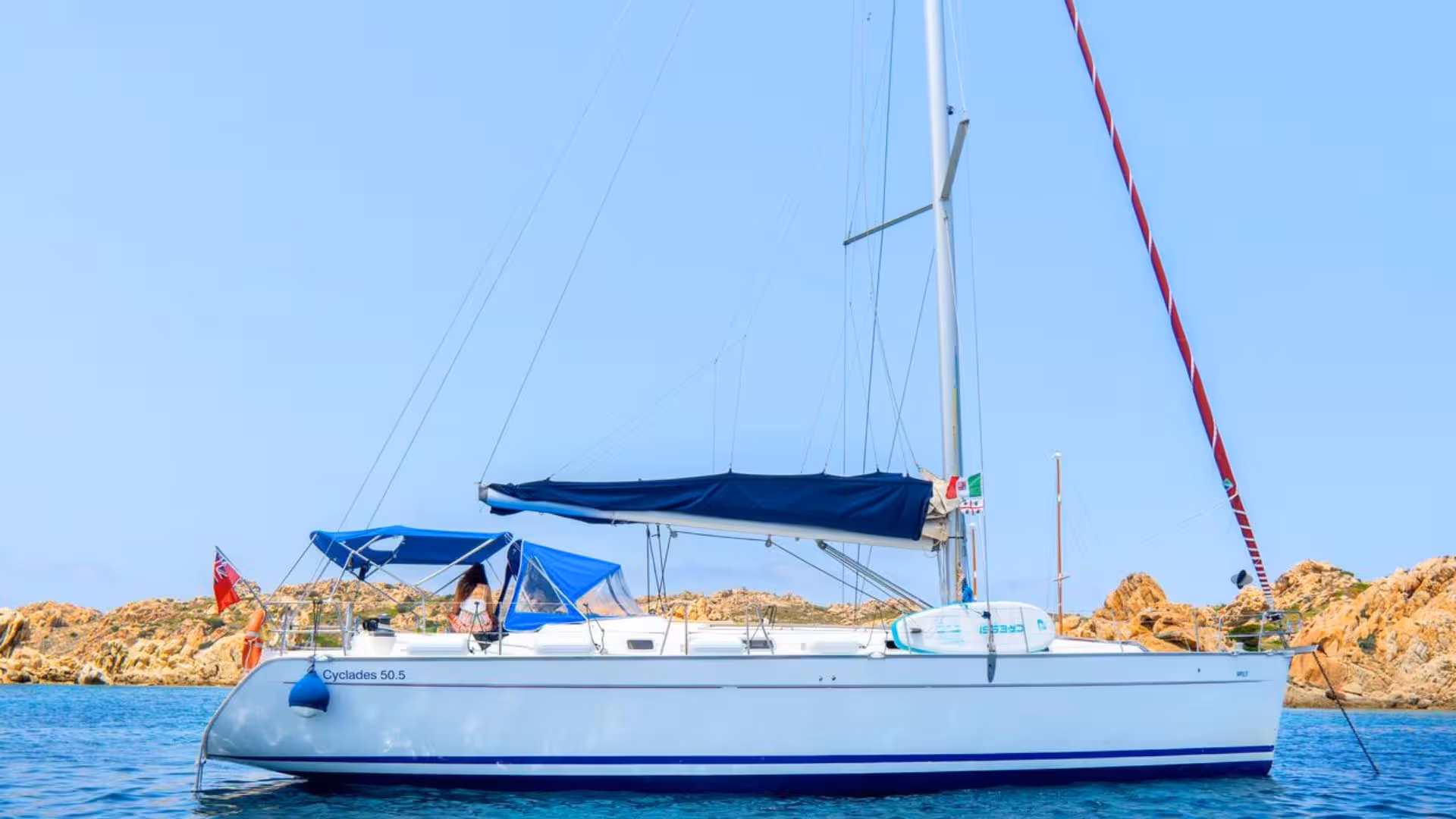 White sailboat anchored in clear waters near rocky shores on a La Maddalena Archipelago sailing tour from Santa Teresa di Gallura.