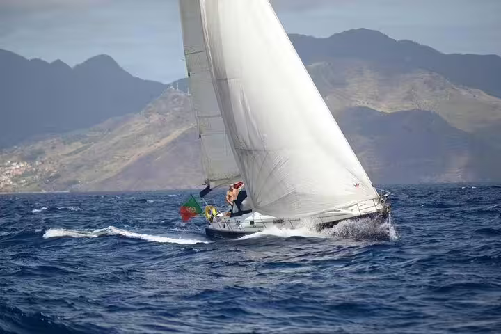 Sailboat gliding on Madeira's South Coast with scenic mountain backdrop, perfect for a half-day sailing adventure.