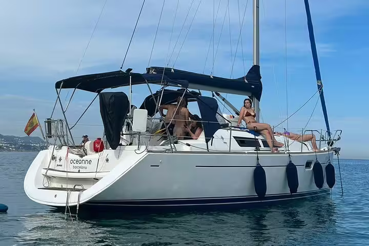 Sailboat with relaxed passengers enjoying a sunny day on the Mediterranean Sea during the Ibiza and Formentera full-day sailing tour.