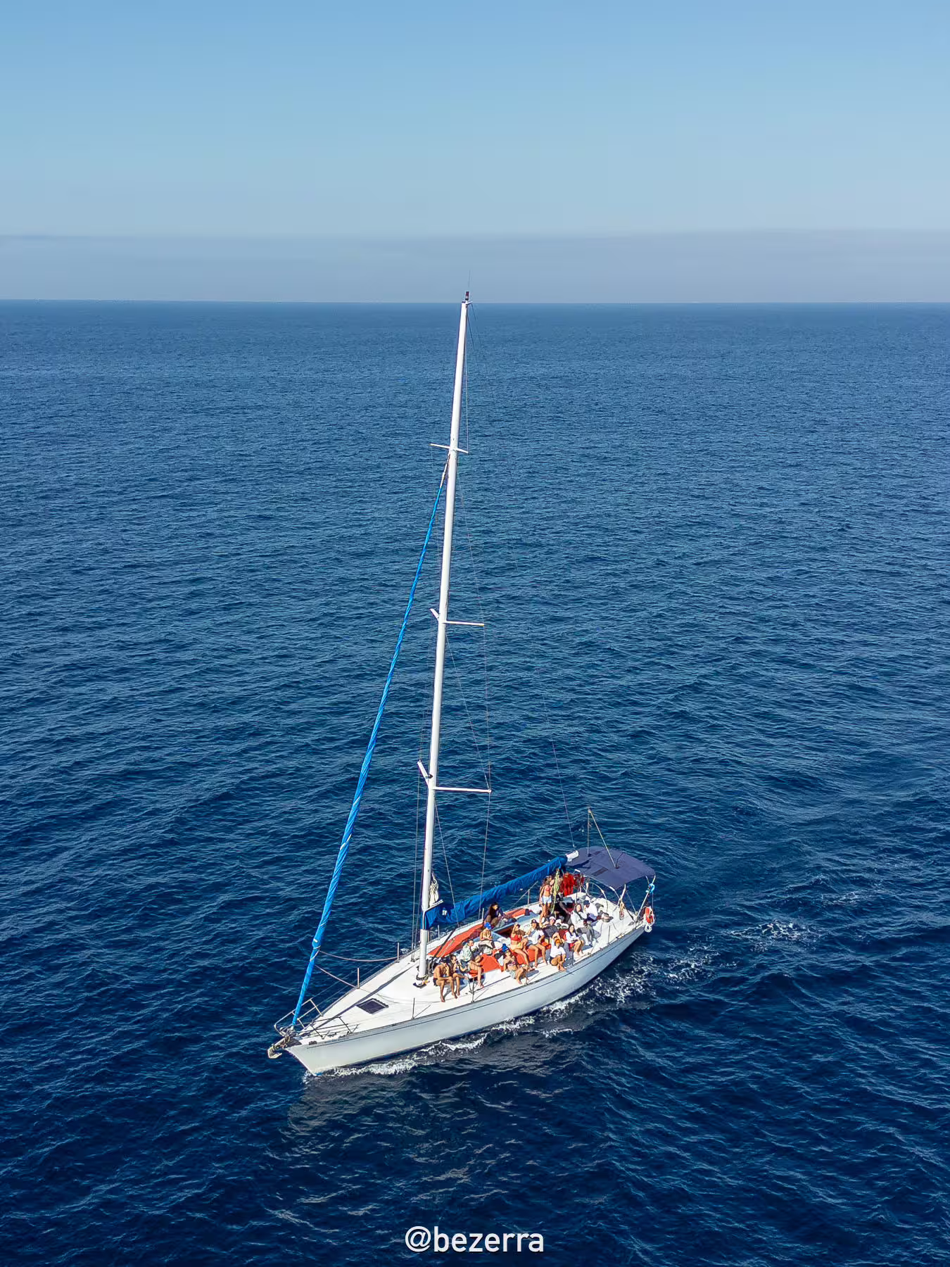 Aerial view of sailboat with guests on whale watching expedition, cruising open sea for whales and dolphins
