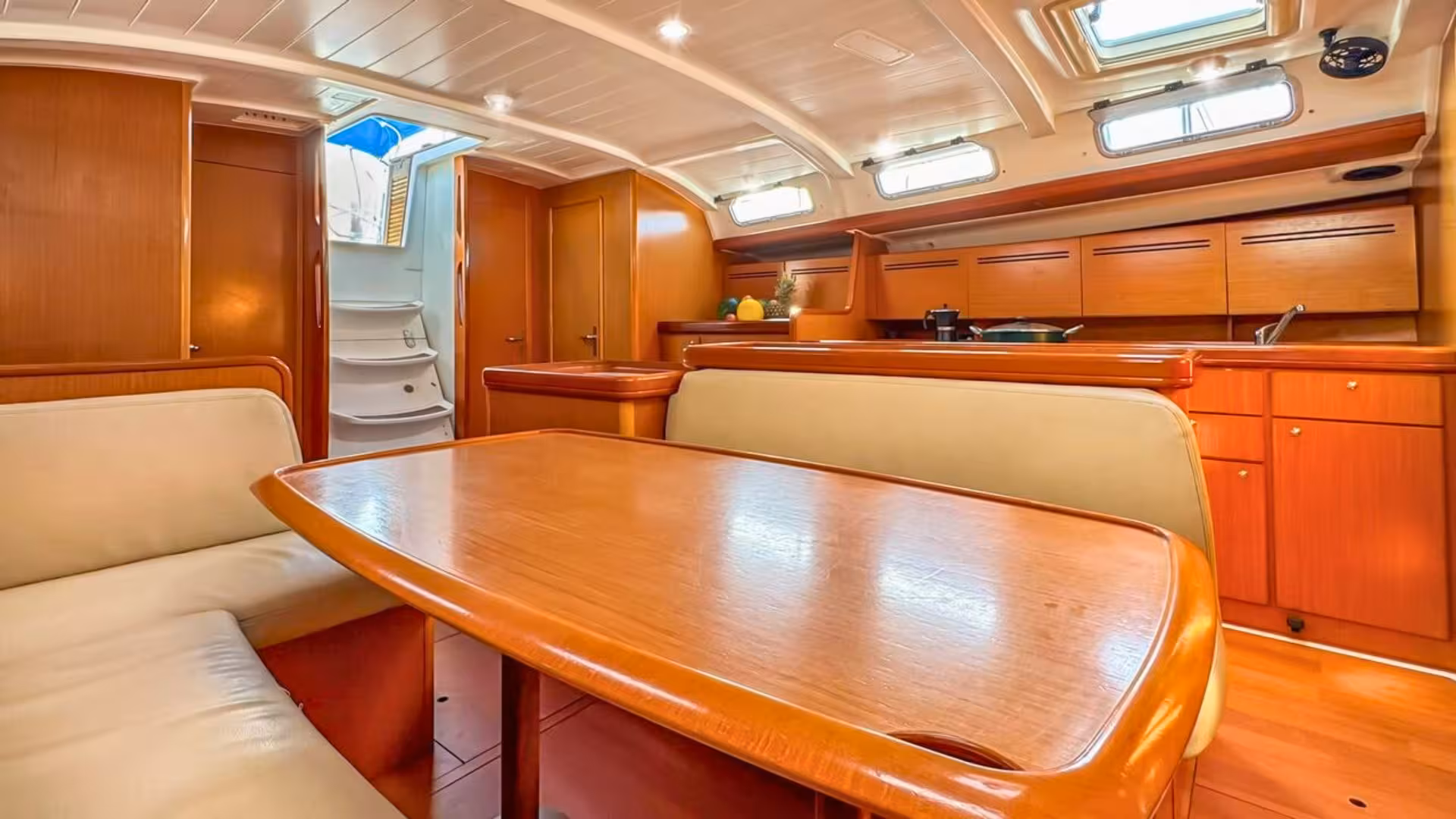 Elegant wooden interior of a sailboat kitchen, showcasing dining and cooking amenities on a Corsica sailing trip.