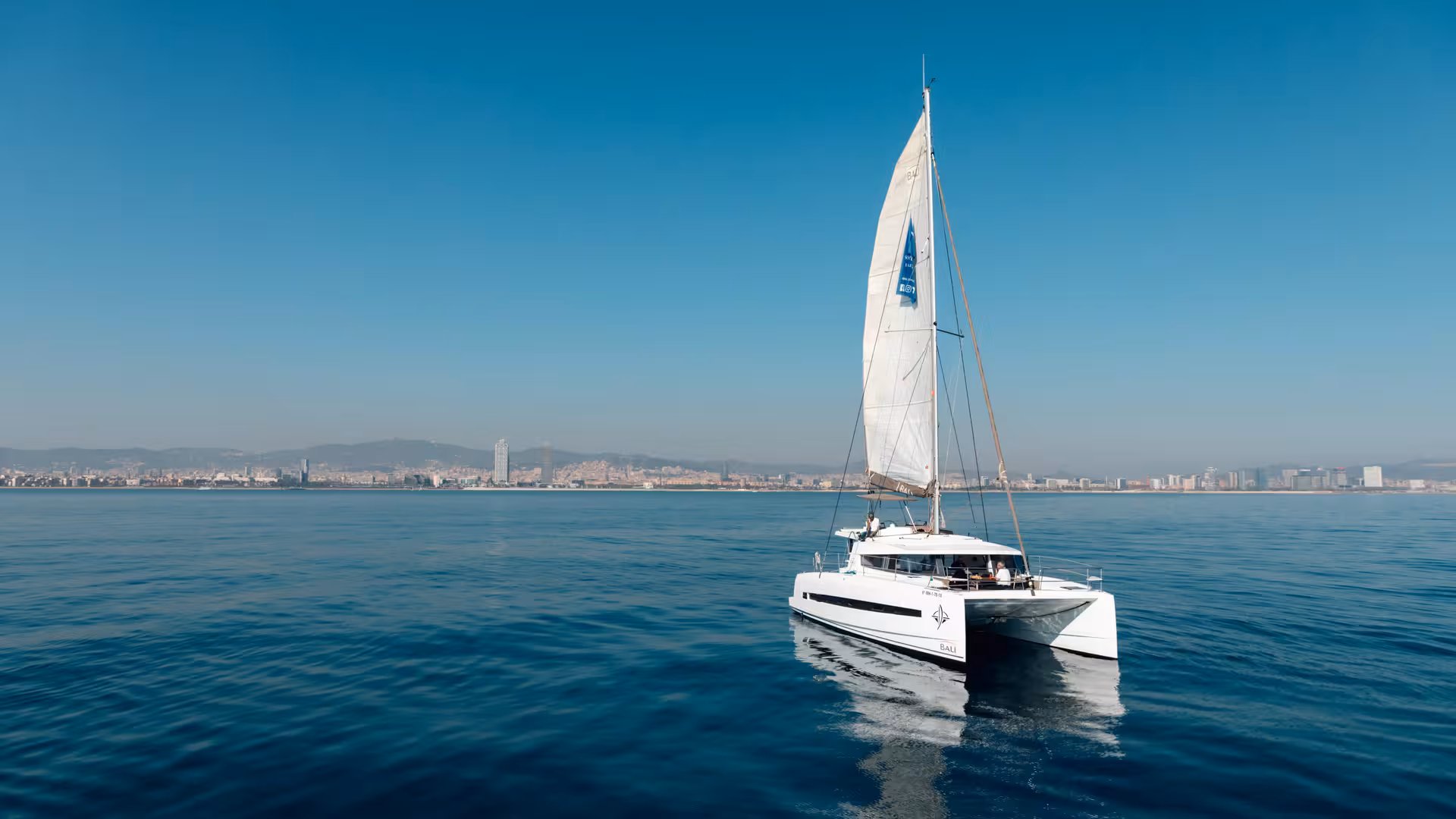 Sailing catamaran cruise hosting a relaxing tea ceremony experience on calm sea with city skyline backdrop