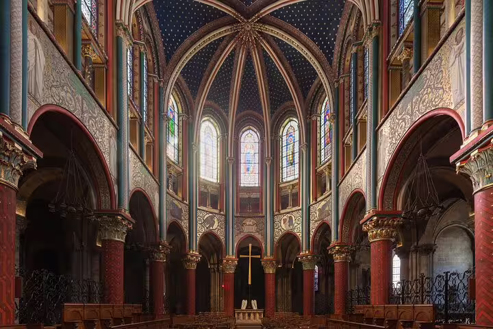 Ornate Gothic interior of Saint-Germain-des-Prés church with colorful arches, stained glass windows, and golden cross