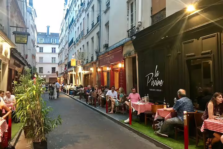 Lively Saint-Germain narrow street lined with outdoor restaurant terraces and diners in Paris at dusk