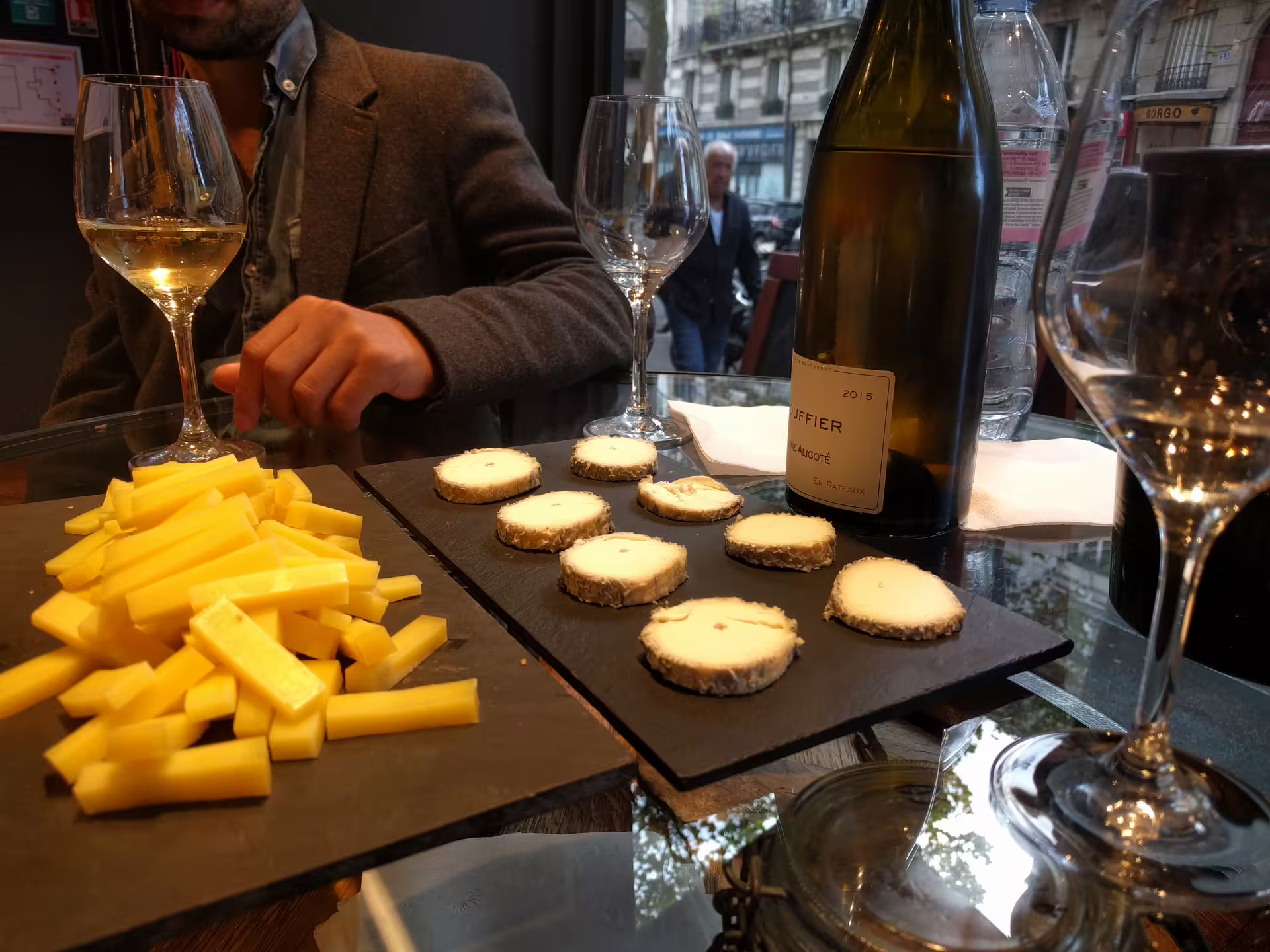 Wine and cheese tasting board with white wine bottle and glasses at Saint-Germain Paris wine bar